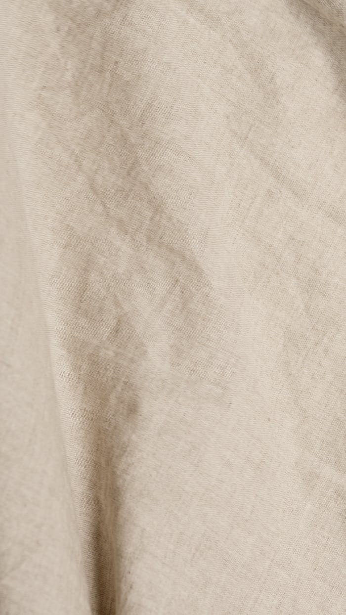 Close-up of a beige linen fabric displaying texture and folds for textile use.