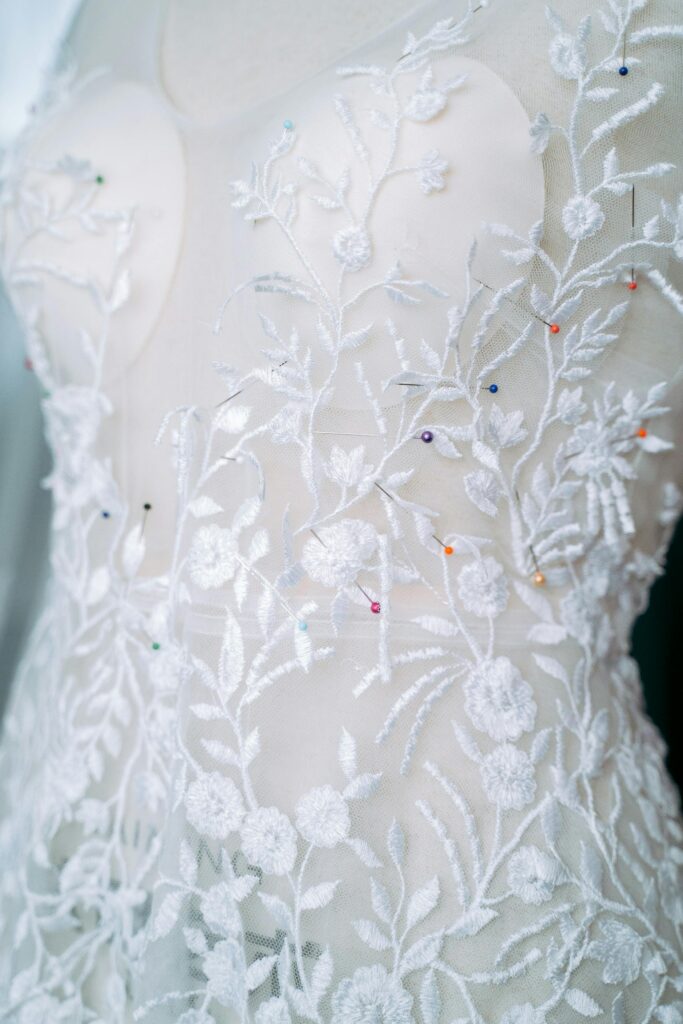 Detailed close-up of a white lace wedding dress showcasing intricate floral embroidery.